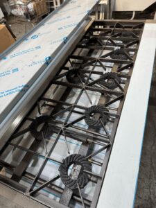 Close-up of the multi-burner gas cooker burner deck with cast-iron pan supports, in the workshop
